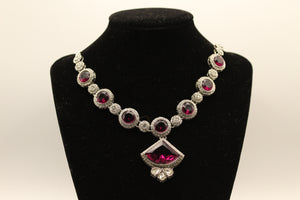 Silver-tone necklace of purple crystals in pave halos with a fan-cut purple centrepiece on a black bust
