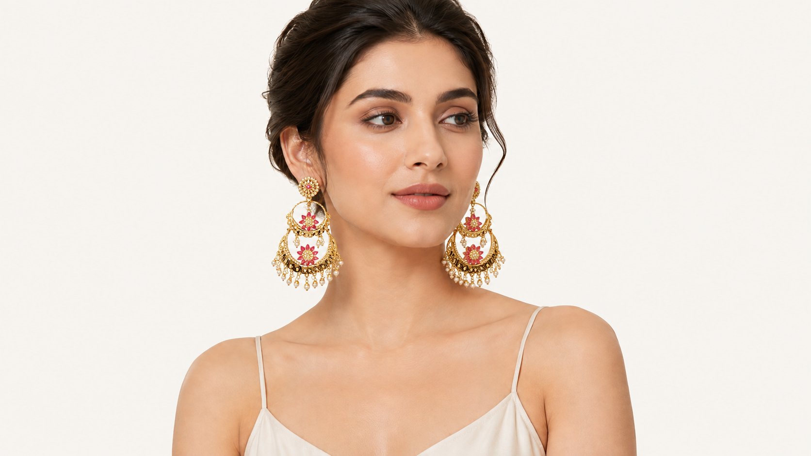 Model wearing gold chandbali earrings with pink stones and pearl drops
