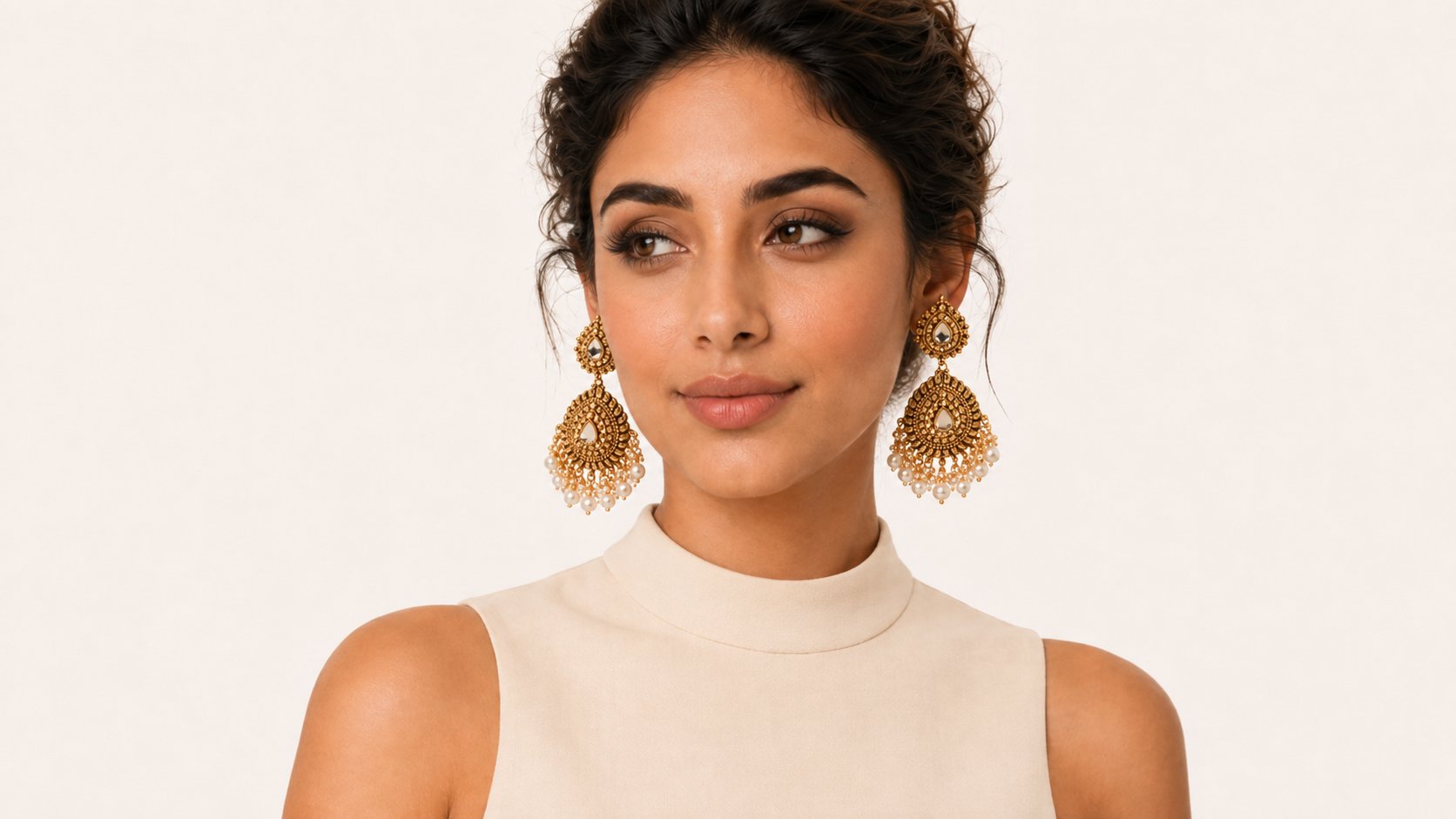 Model wearing antique gold teardrop earrings with pearl clusters