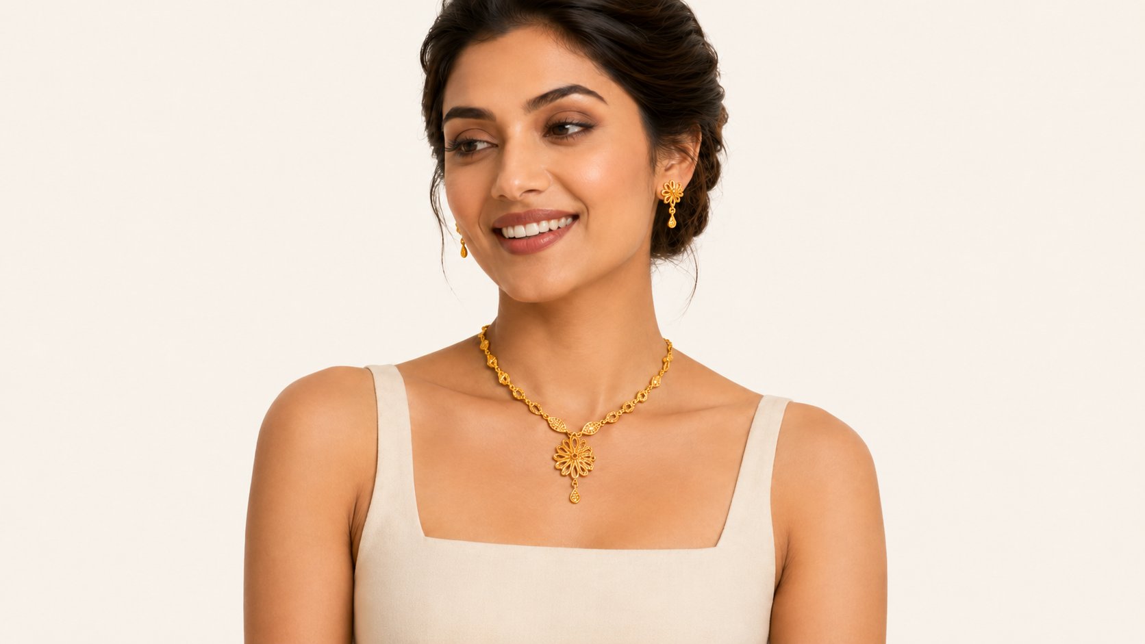 Model wearing a gold floral necklace set with matching drop earrings